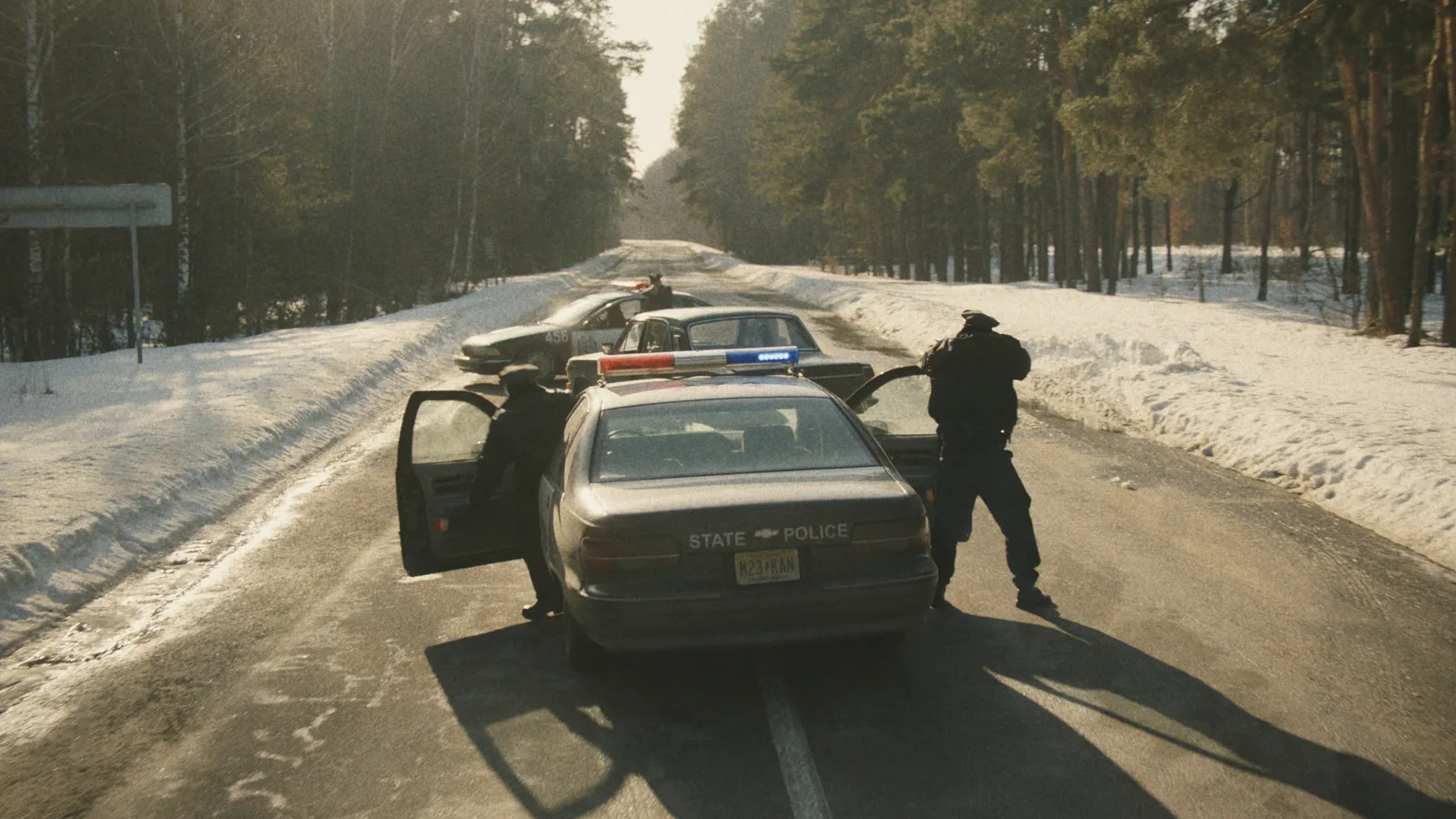 Police officers at their cars on a snowy road, in the Indie 16 look